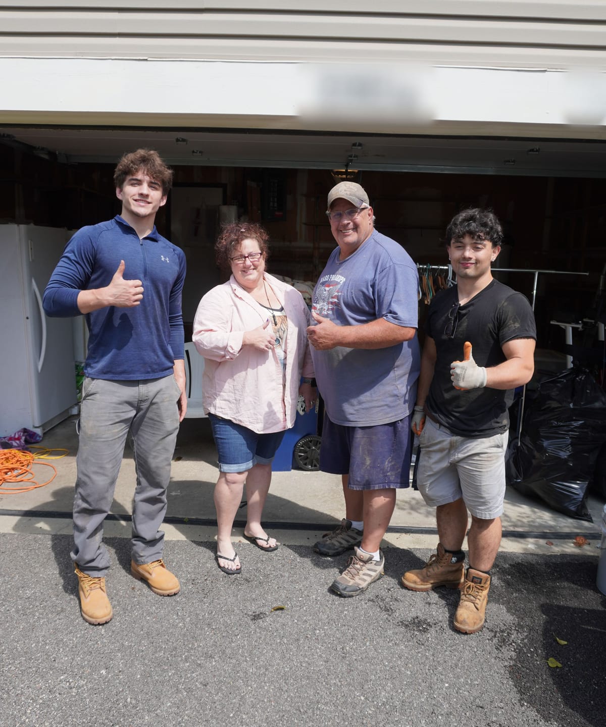 Two Safe Move movers giving a thumbs up with the homeowners in front of their garage